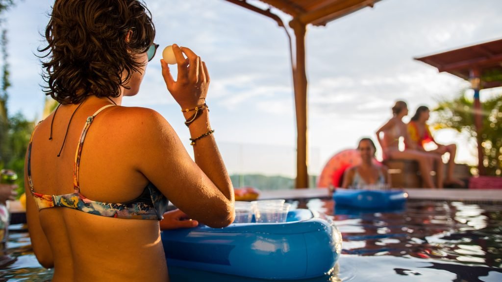 Grupo de chicas jugando al beer pong en una piscina durante una despedida de soltera
