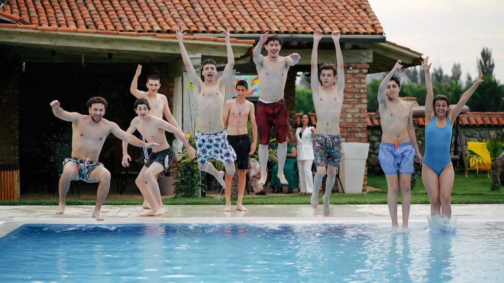 Grupo de chicos y chicas disfrutando de una piscina durante una despedida
