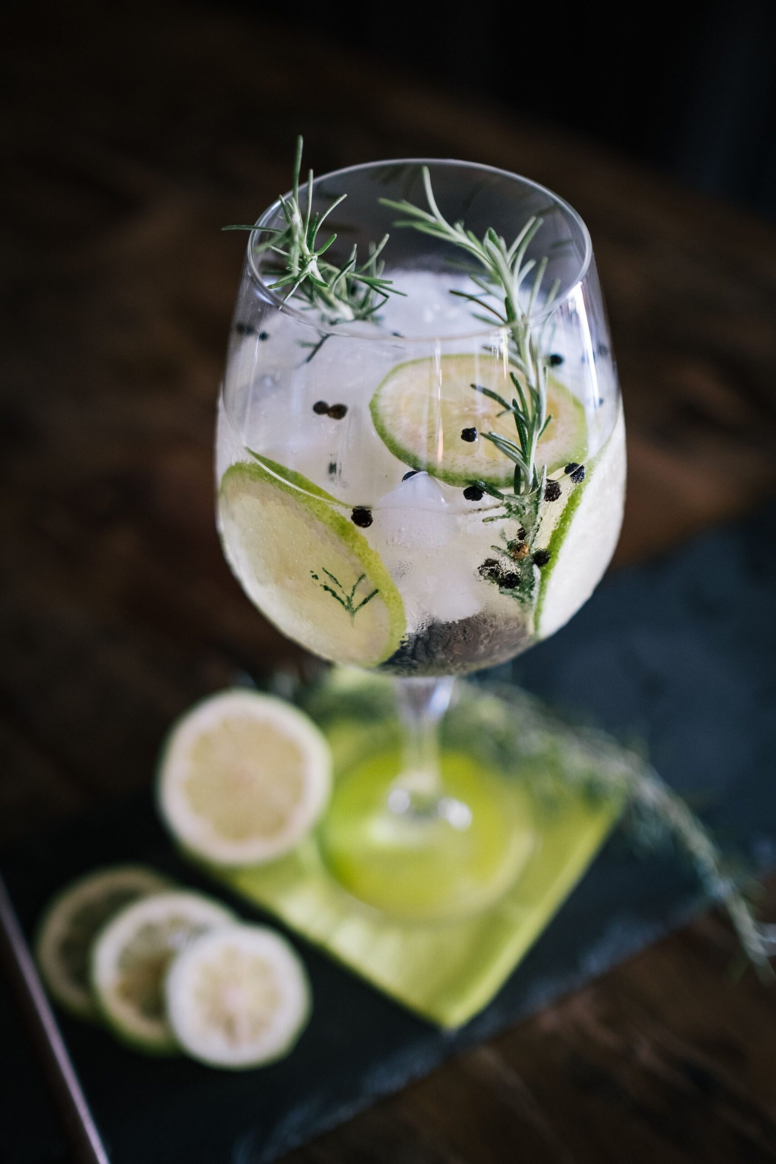 Grupo de amigos elaborando gin-tonics con cítricos y elementos aromáticos durante una actividad de coctelería